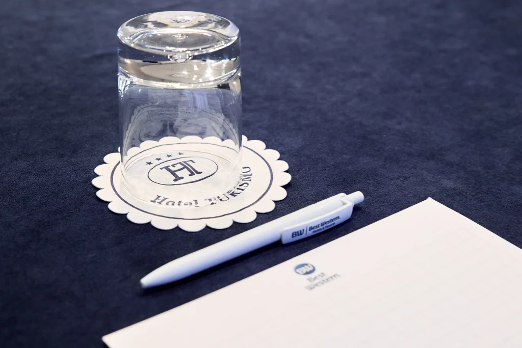 Detail of a meeting room table, with pad, pen and glass, with coaster with hotel logo